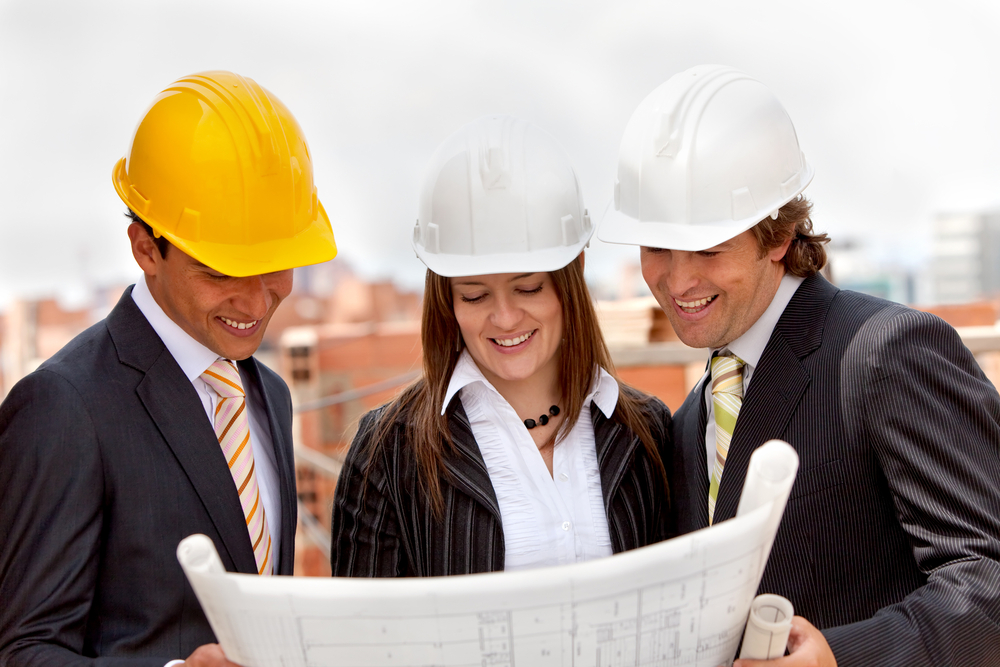 Group of architects at a construction site looking at the blueprints