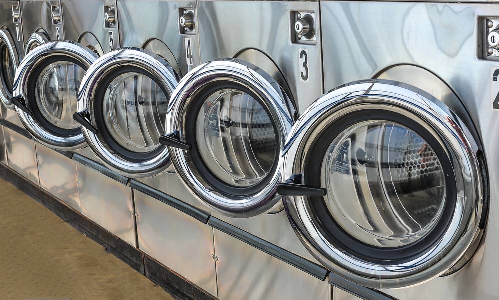 Row of industrial laundry machines in commercial laundry